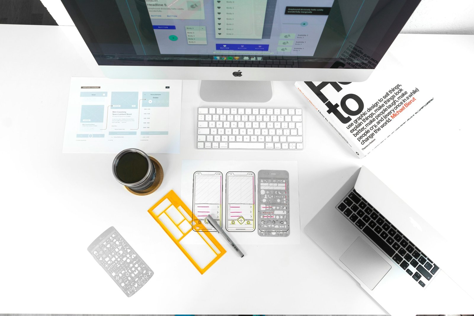 Modern workspace with web design mockups and construction company branding materials on a desk.